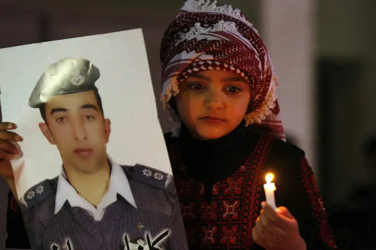 Menina jordaniana segura foto do piloto Muath al-Kasaesbeh, capturado em dezembro pelo EI (Muhammad Hamed/Reuters)