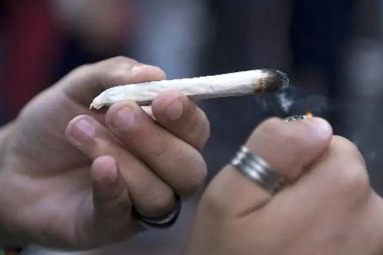 
	Jovem acende um cigarro de maconha: medida pode fazer com que dependentes tenham acesso facilitado &agrave; sa&uacute;de
 (Pablo Porciuncula/AFP)