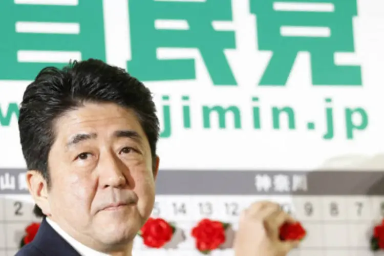 O ex-primeiro-ministro Shinzo Abe marca nomes de candidatos que são esperados para ganhar, na sede do PLD em Tóquio (REUTERS / Yuriko Nakao)