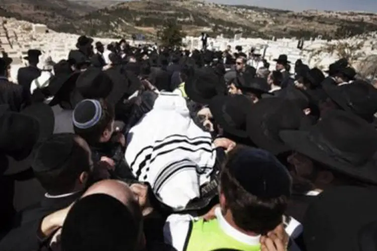 Judeus ultraortodoxos carregam um dos corpos durante a cerimônia de enterro, em Jerusalém, das vítimas da matança: três crianças judias foram mortas (Menahem Kahana/AFP)