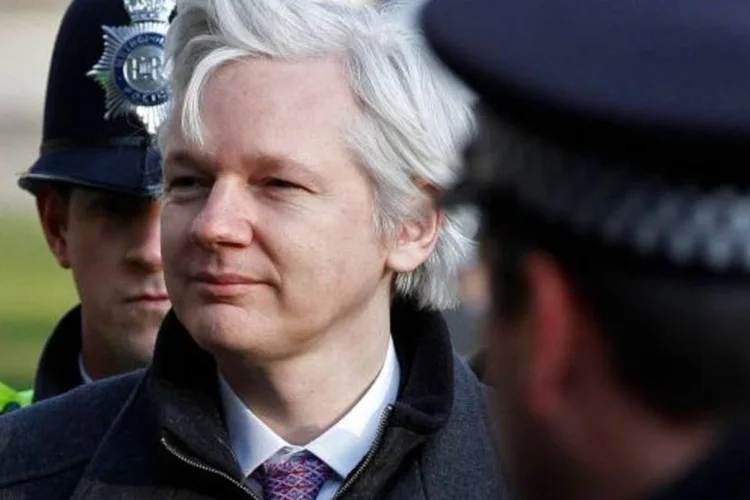 Julian Assange acompanhado por policiais, no Reino Unido (Stefan Wermuth/Reuters)