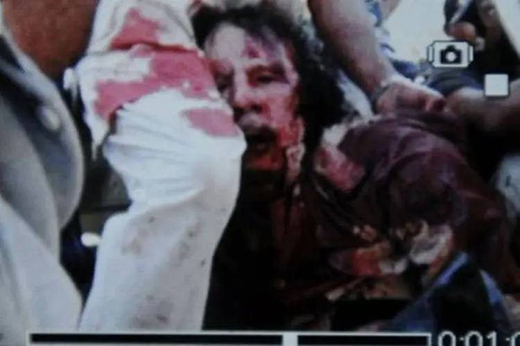 Imagem capturada de câmera de telefone celular mostra a detenção de Muammar Kadafi, que aparece muito ferido (AFP)