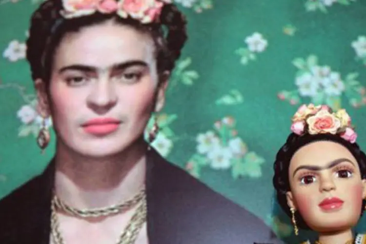 
	Boneca de Frida &eacute; vista em frente a uma foto da artista em uma f&aacute;brica: Frida criou roupas para esconder imperfei&ccedil;&otilde;es e promover sua identidade &eacute;tnica
 (Susana Gonzalez/AFP)