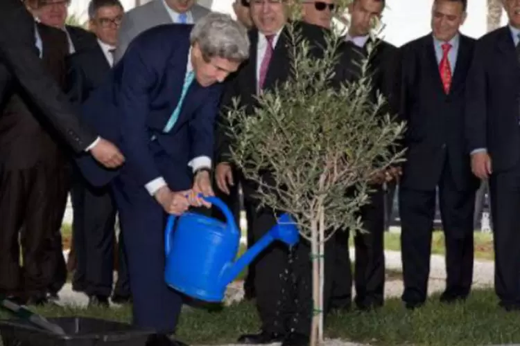 John Kerry rega uma árvore que plantou com o colega da Argélia, Ramtane Lamamra: Kerry afirmou que a paz enfrenta "ameaças mais complexas que nunca" (Jacquelyn Martin/AFP)