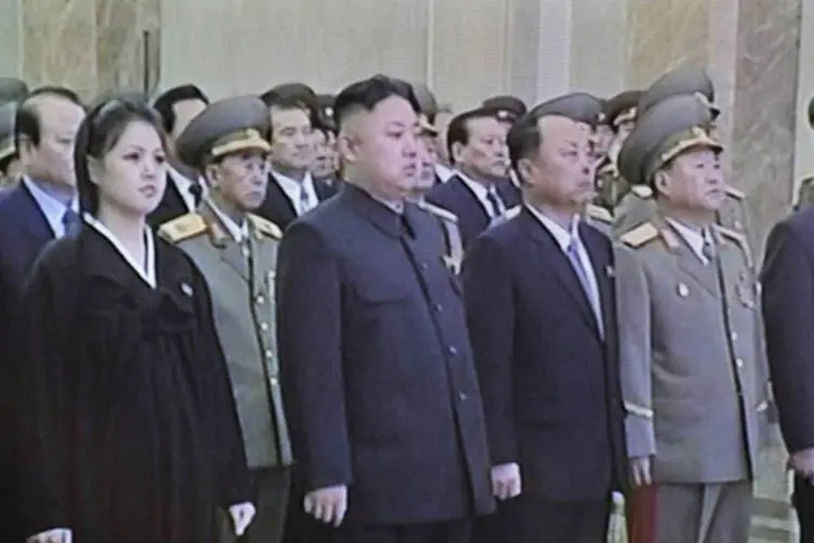 
	O l&iacute;der norte-coreano Kim Jong-Un (C) e sua esposa Ri Sol-Ju (E) participam de cerim&ocirc;nia em Pyongyang: a foto levantou suspeitas sobre uma poss&iacute;vel gravidez
 (North Korean TV/AFP)