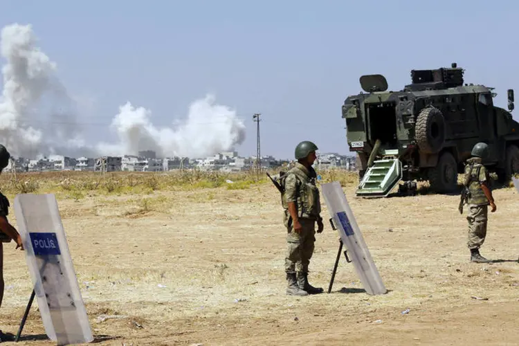 Soldados turcos fazem guarda e fumaça é vista na cidade de Kobani (Reuters)