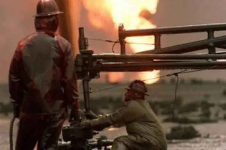 Bombeiros trabalham para conter explosão em campo de petróleo no Kuwait, após retirada dos soldados iraquianos, em 1991