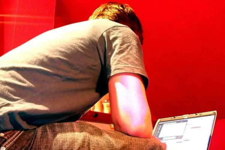 Jovem trabalhando com um notebook em um quarto vermelho (Stock.XCHNG)