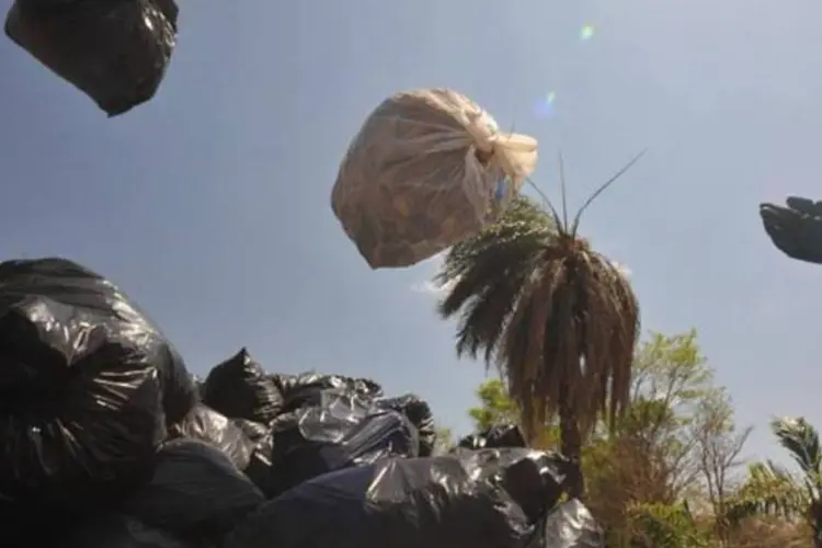 
	Pessoas jogam sacos de lixo: em 2003, a Rhodia j&aacute; havia obtido o aval dos &oacute;rg&atilde;os ambientais oficiais para transportar e incinerar parte do material contaminado
 (Elza Fiuza/ABr)