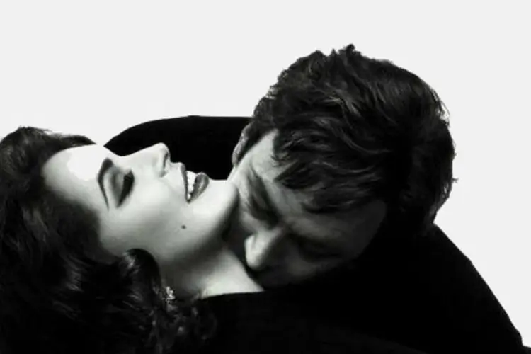 Fotografia oficial, em preto e branco, mostra a atriz sendo beijada por Grant Bowler, ator que interpreta Burton (Divulgação)
