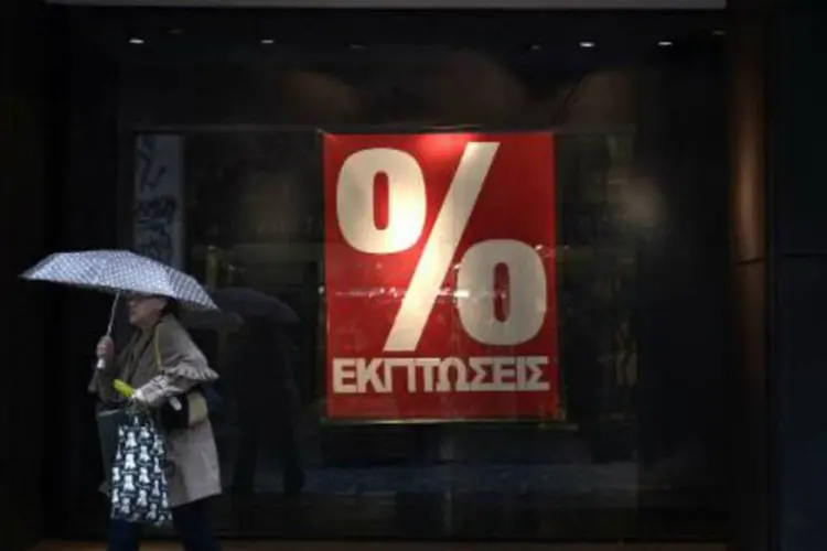 Mulher é vista em frente a loja de Atenas, no primeiro dia das liquidações de inverno (Louisa Gouliamaki/AFP)