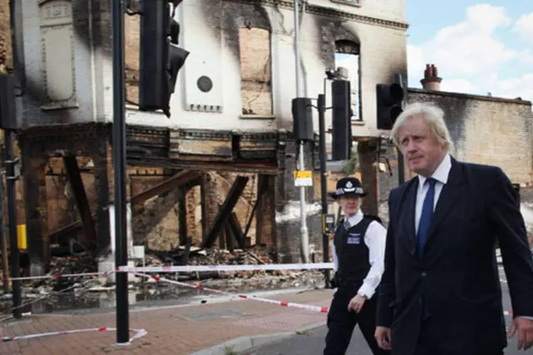 O prefeito de Londres, Boris Johnson, caminha com a superintende da Polícia, Jo Oakley, próximo a uma loja queimada durante distúrbios em Londres (Peter Macdiarmid/Getty Images)