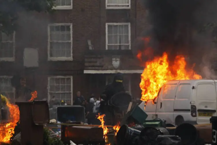 Jovens colocam fogo em barricada que eles construíram durante onda de violência em Hackney, Londres
