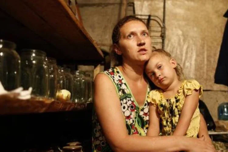 Mãe e filha se protegem dos bombardeios no porão de casa, perto de Donetsk (Max Vetrov/AFP)