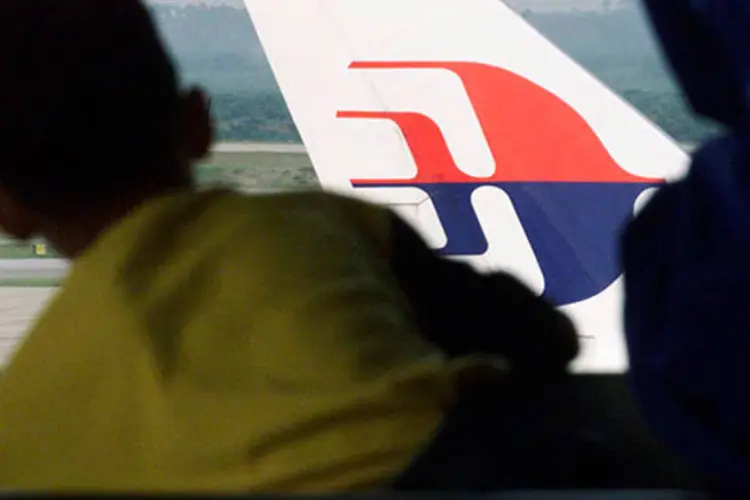 Menino olha para um avião da Malaysian Airlines no Aeroporto Internacional de Kuala Lumpur (REUTERS/Bazuki Muhammad/Files)