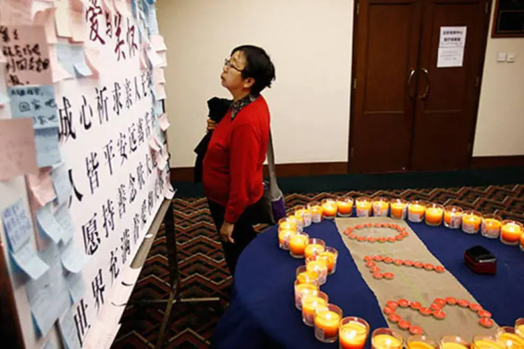 Uma mulher cujo marido estava a bordo do voo MH370 olha mensagem em quadro dedicado a passageiros em hotel na China (REUTERS/Kim Kyung-Hoon)