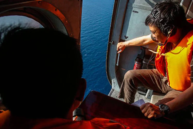 
	Investigador do Vietn&atilde; olha pra fora de um helic&oacute;ptero durante miss&atilde;o de busca: um suposto fragmento do avi&atilde;o, que pode ser de uma janela ou de uma porta de emerg&ecirc;ncia, foi localizado
 (REUTERS/Athit Perawongmetha)