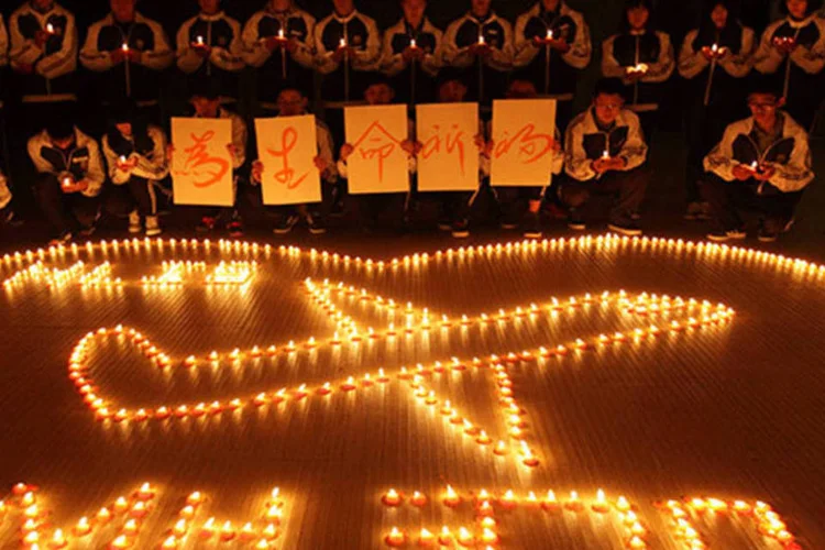 Estudantes acendem velas para rezar por passageiros a bordo do avião desaparecido da Malaysia Airlines (REUTERS/Stringer)
