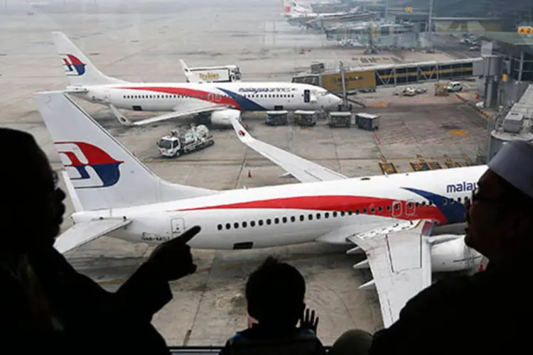 Pessoas olham para o avião da Malaysia Airlines no Aeroporto de Kuala Lumopur: o voo MH370 saiu no último sábado de Kuala Lumpur rumo a Pequim, mas desapareceu (REUTERS/Damir Sagolj)