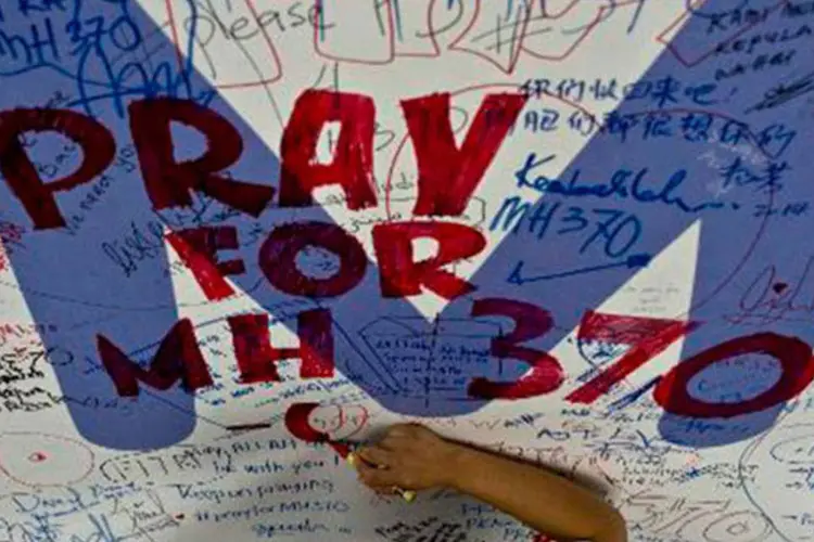 Funcionário da Malaysia Airlines escreve mensagem de apoio aos passageiros do voo desaparecido MH370 no Aeroporto Internacional de Kuala Lumpur (MANAN VATSYAYANA/AFP)