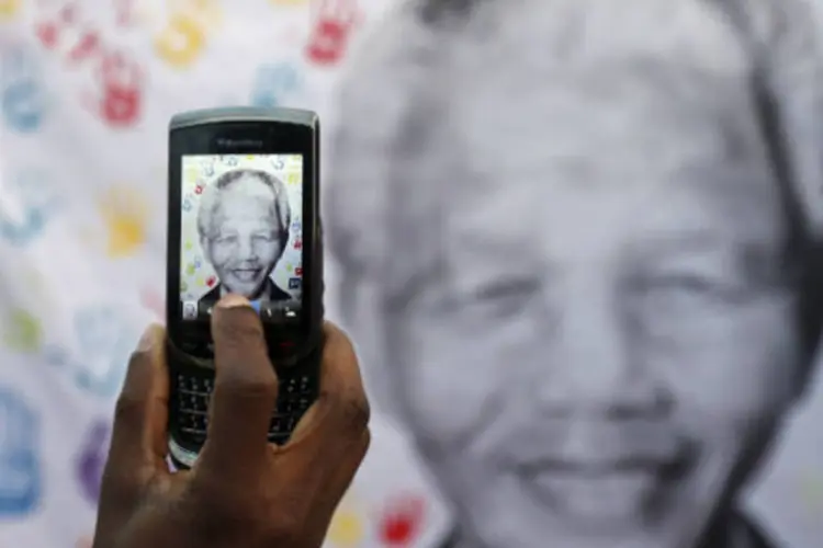 
	Homem tira foto de um cartaz com a imagem de Nelson Mandela durante as comemora&ccedil;&otilde;es de seu anivers&aacute;rio, em frente ao hospital de Pret&oacute;ria onde o ex-presidente da &Aacute;frica do Sul est&aacute; internado
 (REUTERS/Siphiwe Sibeko)