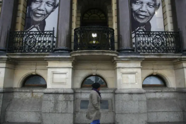 Mulher passa em frente a banners com a imagem do ex-presidente sul-africano Nelson Mandela ( REUTERS/Mark Wessels)