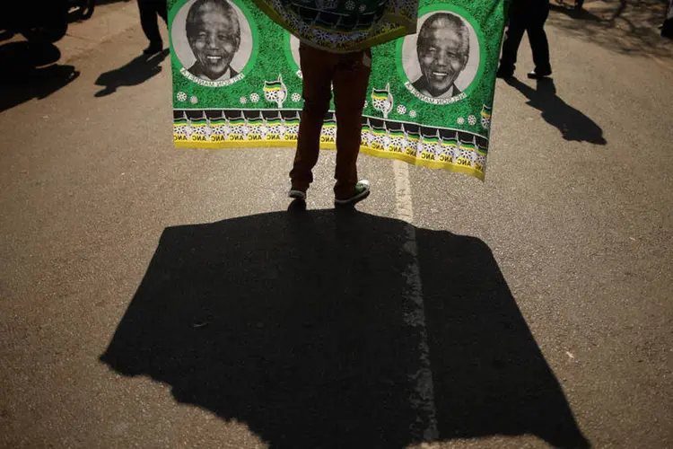 Homem vende bandeira com a imagem do ex-presidente Nelson Mandela em frente ao Mediclinic Heart Hospital  (Chip Somodevilla/Getty Images)