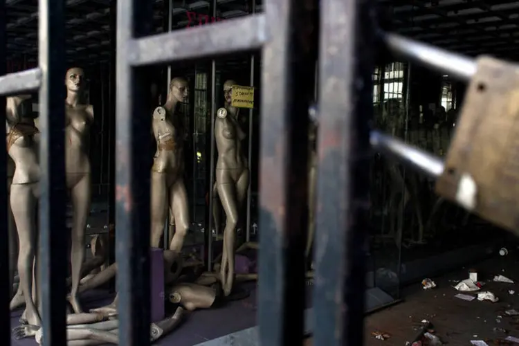 Manequins atrás do portão de uma loja fechada em Atenas, capital da Grécia (Angelos Tzortzinis/Bloomberg)