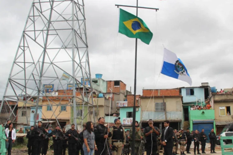 As bandeiras do Brasil e do Rio de Janeiro são hasteadas, na comunidade João Goulart, em Manguinhos, marcando a ocupação das forças de segurança na área (Vladimir Platonow/AFP)