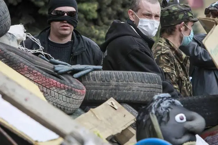 Manifestantes pró-Rússia com máscaras guardam uma barricada na frente do escritório do serviço de segurança SBU, tomado por eles, em Luhansk, no leste da Ucrânia (Shamil Zhumatov/Reuters)