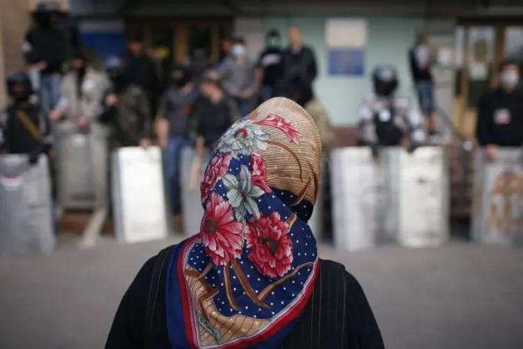 Mulher em frente a manifestantes pró-Rússia durante protesto no conselho distrital de Donetsk, no leste da Ucrânia (Marko Djurica/Reuters)