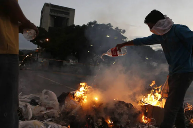 
	Manifestantes da oposi&ccedil;&atilde;o pr&oacute;ximos a barricada: ao menos seis pessoas morreram desde o come&ccedil;o dos protestos, cinco baleadas e uma atropelada
 (Marco Bello/Reuters)