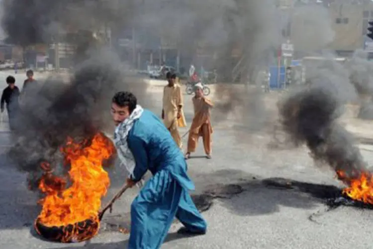 Manifestante atea fogo em pneus na rua de Rawalpindi, Paquistão, durante um protesto em 21 de setembro
 (Aamir Qureshi/AFP)