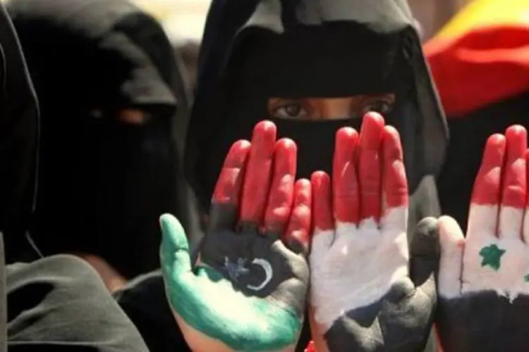 Iemenitas mostram as palmas de suas mãos com as bandeiras de Líbia,Iêmen e Síria (Marwan Naamani/AFP)