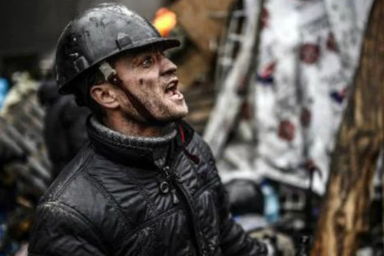 Manifestante se protege atrás de uma barricada erguida na Praça da Independência, em Kiev: prefeito abandona o Partido das Regiões, no poder (Bulent Kilic/AFP)