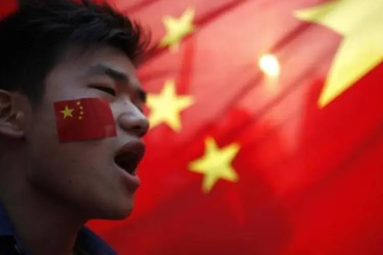 Manisfestante grita durante protesto em frente à bandeira da China em Xangai. Protestos contra o Japão ressurgiram nesta terça-feira em toda a China, no emotivo aniversário da ocupação japonesa no país (Carlos Barria/Reuters)
