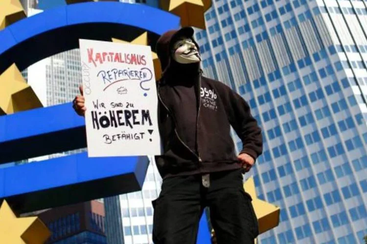Pessoa protesta diante da escultura do euro na frente do BCE, em Frankfurt (Kai Pfaffenbach/Reuters)