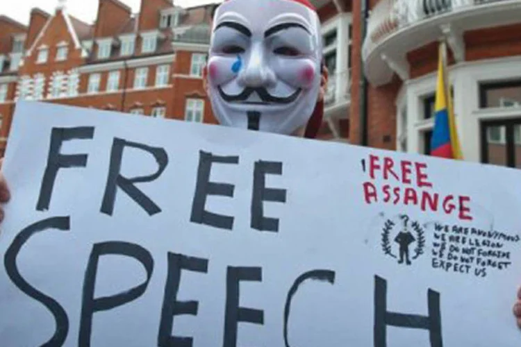 Um mascarado exibe um cartaz pedindo liberdade de expressão diante da embaixada do Equador em Londres nesta quinta (©AFP / Will Oliver)