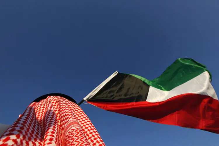 
	Manifestante ergue bandeira do Kuwait: um dos homens era um iraniano que foi condenado &agrave; revelia
 (Manifestante ergue bandeira do Kuwait durante protesto pedindo boicote à eleição)