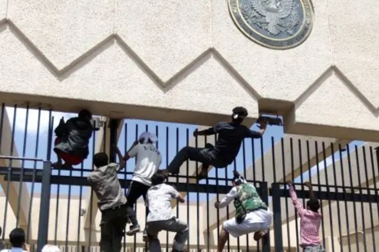 Manifestantes sobem a grade ao redor da embaixada americana para invadí-la, no Iêmen (Mohamed al-Sayaghi/Reuters)