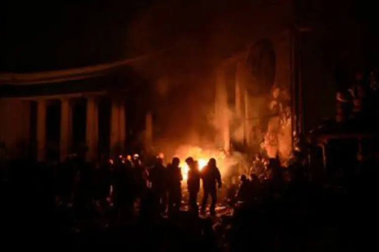 Manifestantes se aquecem em torno de uma fogueira: ocupação do ministério ocorreu depois que o presidente propôs que a oposição dirigisse o governo (Aris Messinis/AFP)