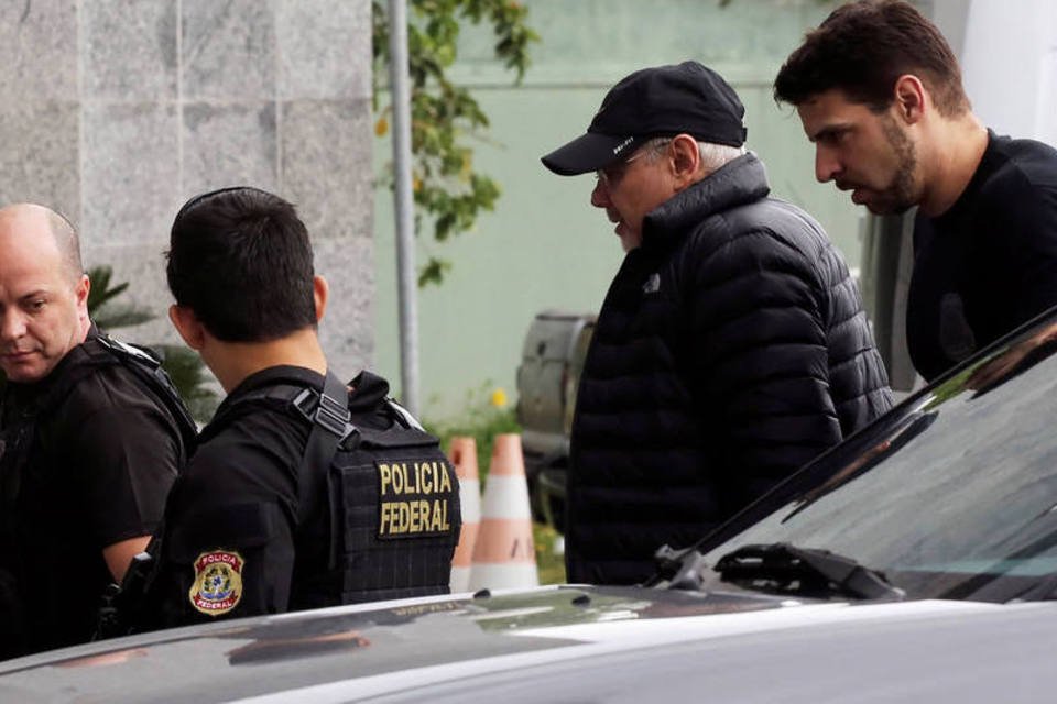 
	Guido Mantega &eacute; conduzido pela PF em SP: ele acompanhava a mulher em uma cirurgia quando foi abordado pelos agentes
 (Nacho Doce/Reuters)
