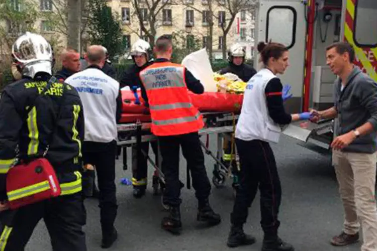 Bombeiros carregam homem ferido em frente ao jornal satírico francês Charlie Hebdo (Philippe Dupeyrat/AFP)