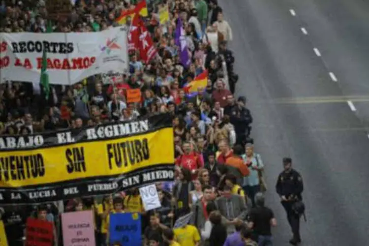 Multidão marcha exibindo cartazes de protesto contra gestão da crise financeira espanhola durante 'panelaço' em Madri (Pedro Armestre/AFP)
