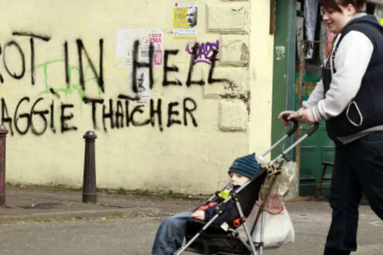
	Mulher empurra carrinho com beb&ecirc; em frente a muro pichado com os dizeres &quot;apodre&ccedil;a no inferno, Margaret Thatcher&quot;, na Irlanda do Norte
 (REUTERS/Cathal McNaughton)