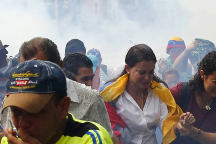 Líder da oposição, Maria Corina Machado, foge do gás lacrimogênio depois dela tentar retomar seu assento na Assembleia Nacional, em Caracas (Jorge Silva/Reuters)