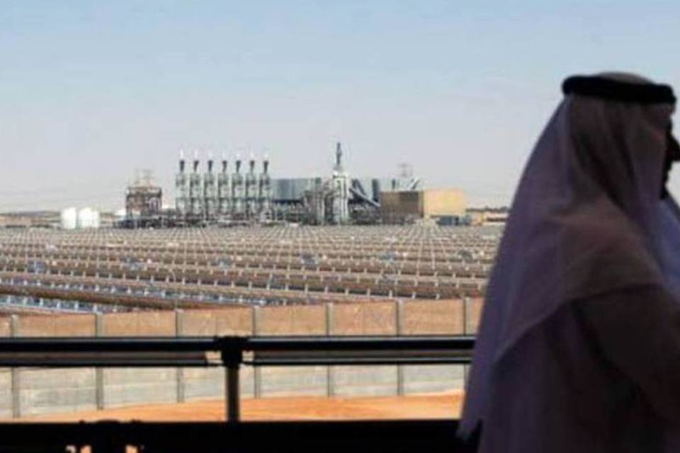 Homem observa de uma sacada a usina de energia solar concentrada Shams-1, nos arredores de Abu Dhabi (©afp.com / Marwan Naamani)