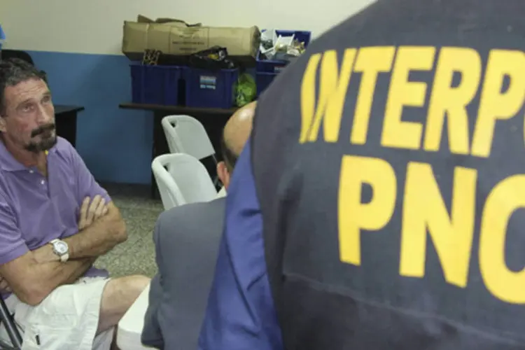 
	John McAfee, pioneiro americano dos antiv&iacute;rus, senta pr&oacute;ximo a agente da Interpol ap&oacute;s a sua deten&ccedil;&atilde;o na Cidade da Guatemala
 (Policia Nacional Civil/Divulgação)