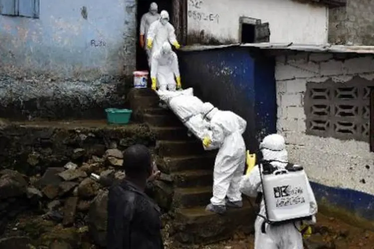 
	M&eacute;dicos da Cruz Vermelha removem o corpo de uma v&iacute;tima do ebola de uma casa
 (Pascal Guyot/AFP)