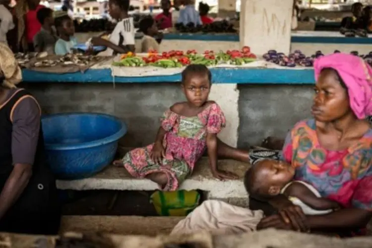 Menina senta em banco num mercado em Dongo, na República Democrática do Congo (Federico Scoppa/AFP)